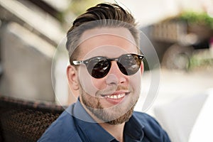 Young handsome man with sunglasses smiling outdoors