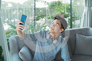 Young handsome man taking selfie wearing wireless headphones listening music