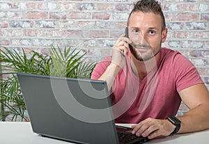 Young handsome man talking on phone in office