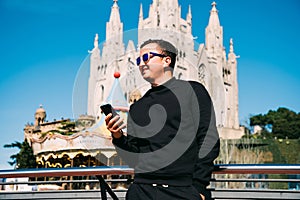 Young handsome man talking on the phone via earbeans standing on the barcelona streets. Summer vocation photo