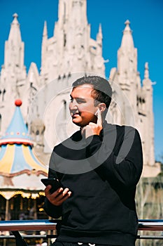 Young handsome man talking via headset standing in front of Tibidabo church. Travel concept photo