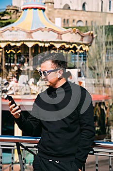 Young handsome man talking via headset standing in front of Tibidabo church. Travel concept photo