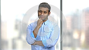 Young handsome man is thinking on blurred background.