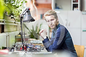 Young handsome man thinking how to solder the circuit board