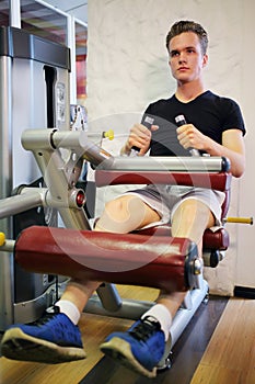 Young handsome man training on fitness machine in