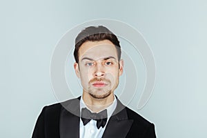 Young handsome man in a tuxedo, setiously looking at the camera