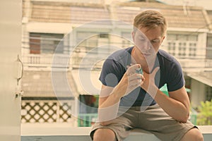 Young handsome man using asthma inhaler at home