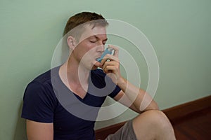 Young handsome man using asthma inhaler at home