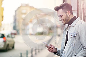 Young handsome man using his cell phone, enjoying a day on the street