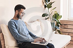 Young handsome man using laptop computer at home. Student men resting  in his room.