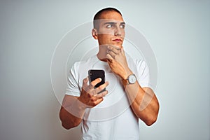 Young handsome man using smartphone over yellow isolated background serious face thinking about question, very confused idea