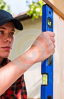 Young handsome man using spirit level in his work