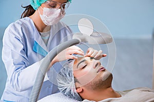 The young handsome man visiting female doctor cosmetologist