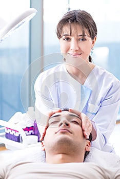 The young handsome man visiting female doctor cosmetologist