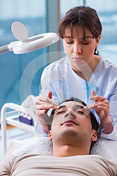 The young handsome man visiting female doctor cosmetologist