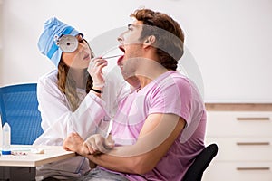 The young handsome man visiting young female doctor otolaryngologist