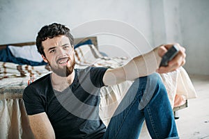 Young handsome man watching TV on a floor at home