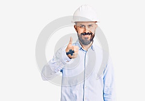 Young handsome man wearing architect hardhat doing happy thumbs up gesture with hand