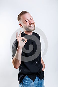 Young handsome man wearing black shirt over gray background doing ok gesture with hand smiling