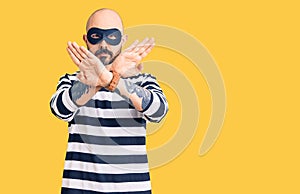 Young handsome man wearing burglar mask rejection expression crossing arms doing negative sign, angry face
