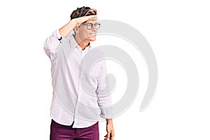 Young handsome man wearing business clothes and glasses very happy and smiling looking far away with hand over head