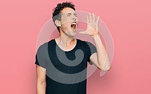 Young handsome man wearing casual black t shirt shouting and screaming loud to side with hand on mouth