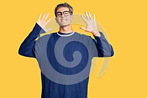 Young handsome man wearing casual clothes and glasses showing and pointing up with fingers number ten while smiling confident and