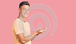 Young handsome man wearing casual clothes pointing aside with hands open palms showing copy space, presenting advertisement