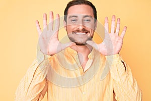 Young handsome man wearing casual clothes showing and pointing up with fingers number ten while smiling confident and happy