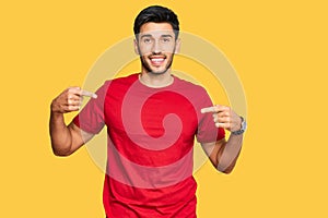 Young handsome man wearing casual red tshirt looking confident with smile on face, pointing oneself with fingers proud and happy