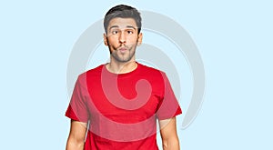 Young handsome man wearing casual red tshirt making fish face with lips, crazy and comical gesture