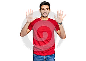 Young handsome man wearing casual red tshirt showing and pointing up with fingers number ten while smiling confident and happy