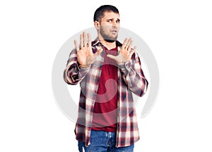 Young handsome man wearing casual shirt moving away hands palms showing refusal and denial with afraid and disgusting expression