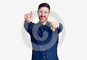 Young handsome man wearing casual shirt pointing to you and the camera with fingers, smiling positive and cheerful