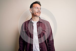 Young handsome man wearing casual shirt standing over isolated white background looking away to side with smile on face, natural