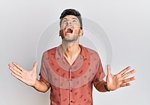 Young handsome man wearing casual summer clothes crazy and mad shouting and yelling with aggressive expression and arms raised