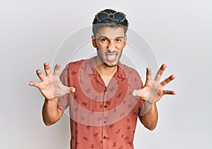 Young handsome man wearing casual summer clothes smiling funny doing claw gesture as cat, aggressive and sexy expression