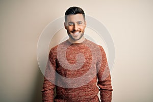Young handsome man wearing casual sweater standing over isolated white background with a happy and cool smile on face