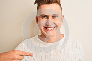 Young handsome man wearing casual t-shirt standing over isolated white background with surprise face pointing finger to himself