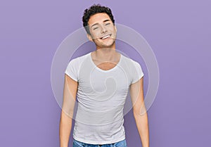 Young handsome man wearing casual white t shirt looking positive and happy standing and smiling with a confident smile showing