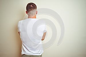 Young handsome man wearing casual white t-shirt over isolated background standing backwards looking away with crossed arms