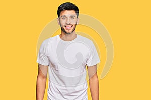 Young handsome man wearing casual white tshirt with a happy and cool smile on face