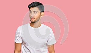 Young handsome man wearing casual white tshirt smiling looking to the side and staring away thinking