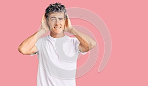 Young handsome man wearing casual white tshirt trying to hear both hands on ear gesture, curious for gossip