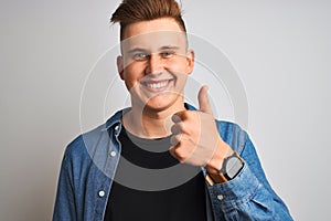 Young handsome man wearing denim shirt standing over isolated white background happy with big smile doing ok sign, thumb up with