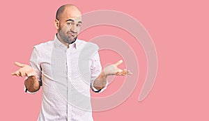 Young handsome man wearing elegant shirt clueless and confused expression with arms and hands raised