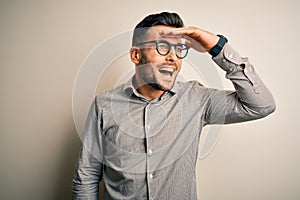 Young handsome man wearing elegant shirt and glasses over isolated white background very happy and smiling looking far away with