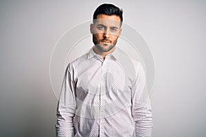 Young handsome man wearing elegant shirt standing over isolated white background Relaxed with serious expression on face