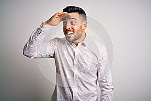 Young handsome man wearing elegant shirt standing over isolated white background very happy and smiling looking far away with hand