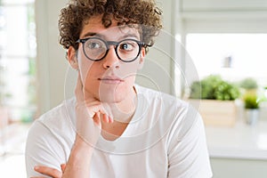 Young handsome man wearing glasses with hand on chin thinking about question, pensive expression